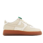 Cream leather low-top sneaker with white laces, green top trim, tan gum sole
