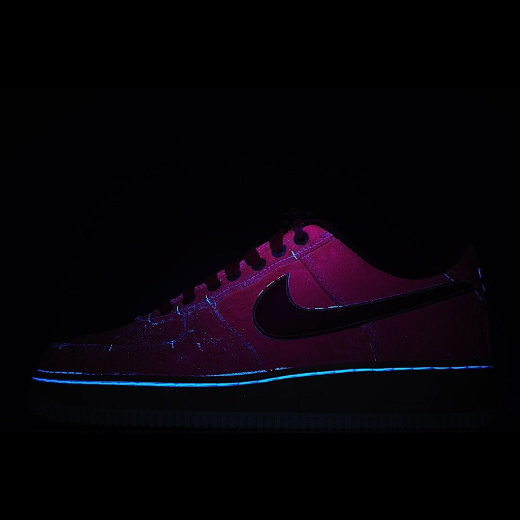 Purple Nike sneaker with black swoosh, glowing accent lights, dark background