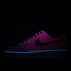 Purple Nike sneaker with black swoosh, glowing accent lights, dark background