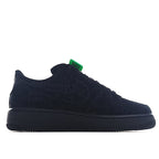 Black low-top lace-up sneaker with textured logo panels and green tag