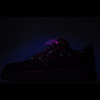 Black low-top sneaker with reflective pattern and green heel tag