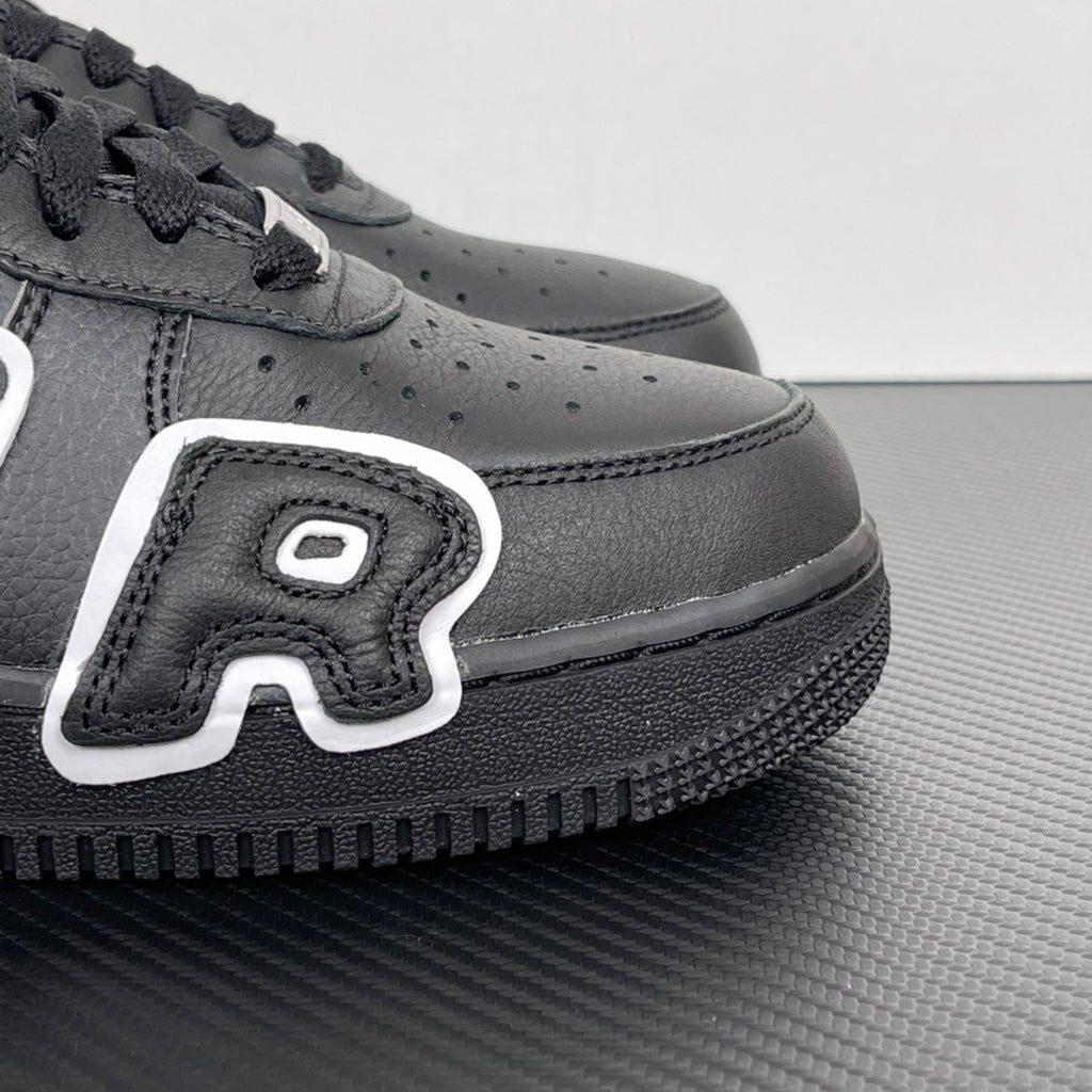 Black sneaker side panel with perforations, white logo patch, and textured sole.