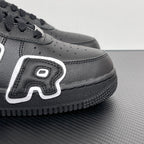 Black sneaker side panel with perforations, white logo patch, and textured sole.