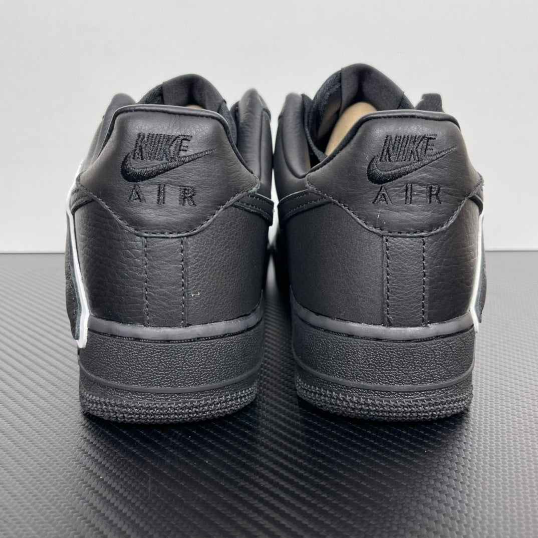 Pair of black sneakers from heel view with NIKE AIR lettering and white sole edge.