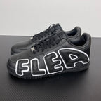 Black low-top sneakers with white flame-style side logos and lace-up front.