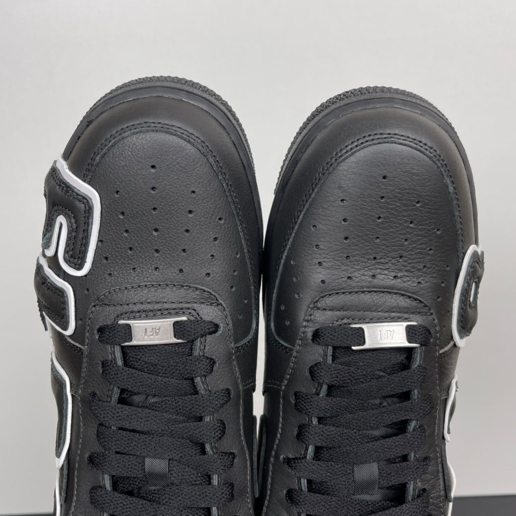 Black sneakers front view with perforated toe box and black lace-up front tabs.
