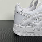 White leather Nike sneaker side with lace panel, embroidered logo patch, and cushioned sole.