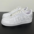 White leather Nike low-top sneakers with lace-up front, perforations, and stitched side panels.