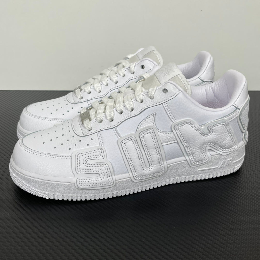White leather Nike low-top sneakers with lace-up front, perforations, and stitched side panels.