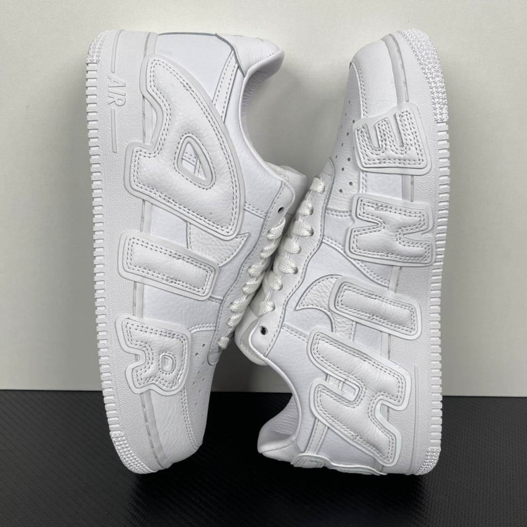 White leather sneakers shown from the side with chunky tread sole and strap-like overlays.