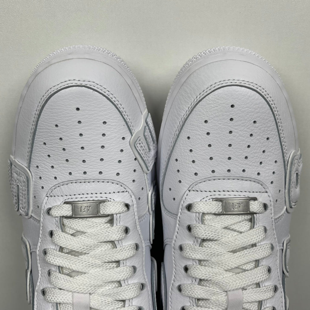 White leather sneaker toe boxes with perforations and lace-up tongues, front view.