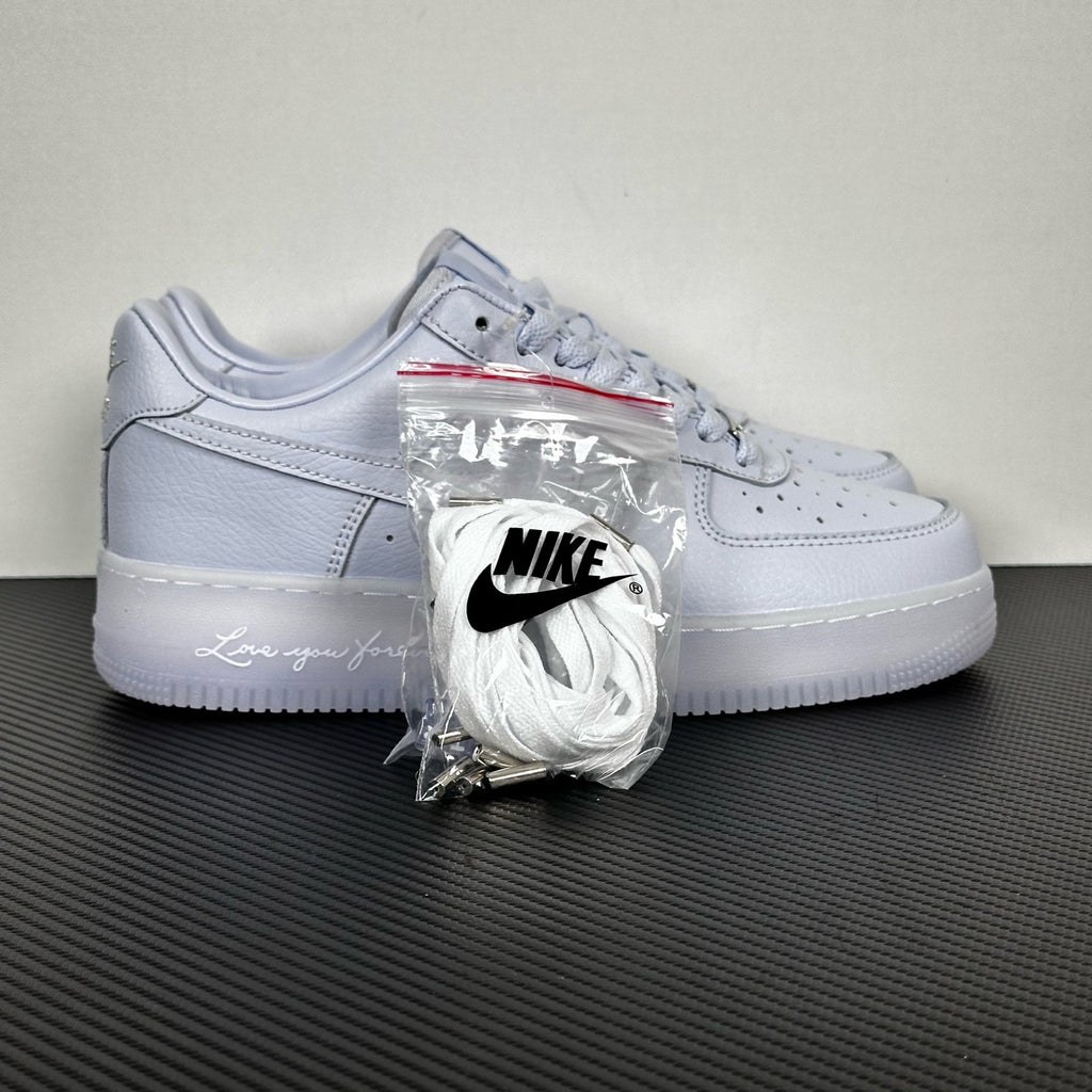 White leather low-top sneakers with Nike swoosh, lace-up, accessory bag attached