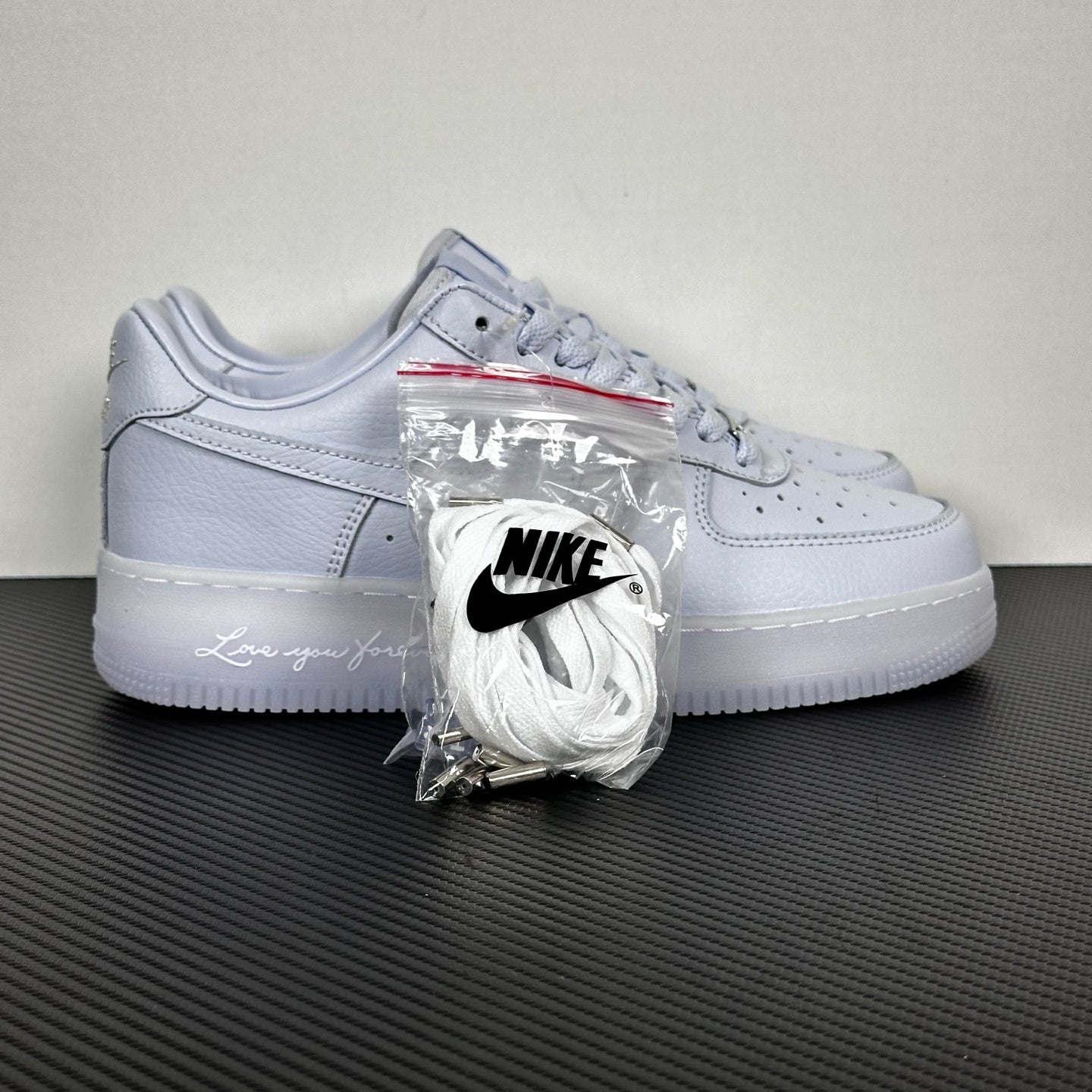 White leather low-top sneakers with Nike swoosh, lace-up, accessory bag attached