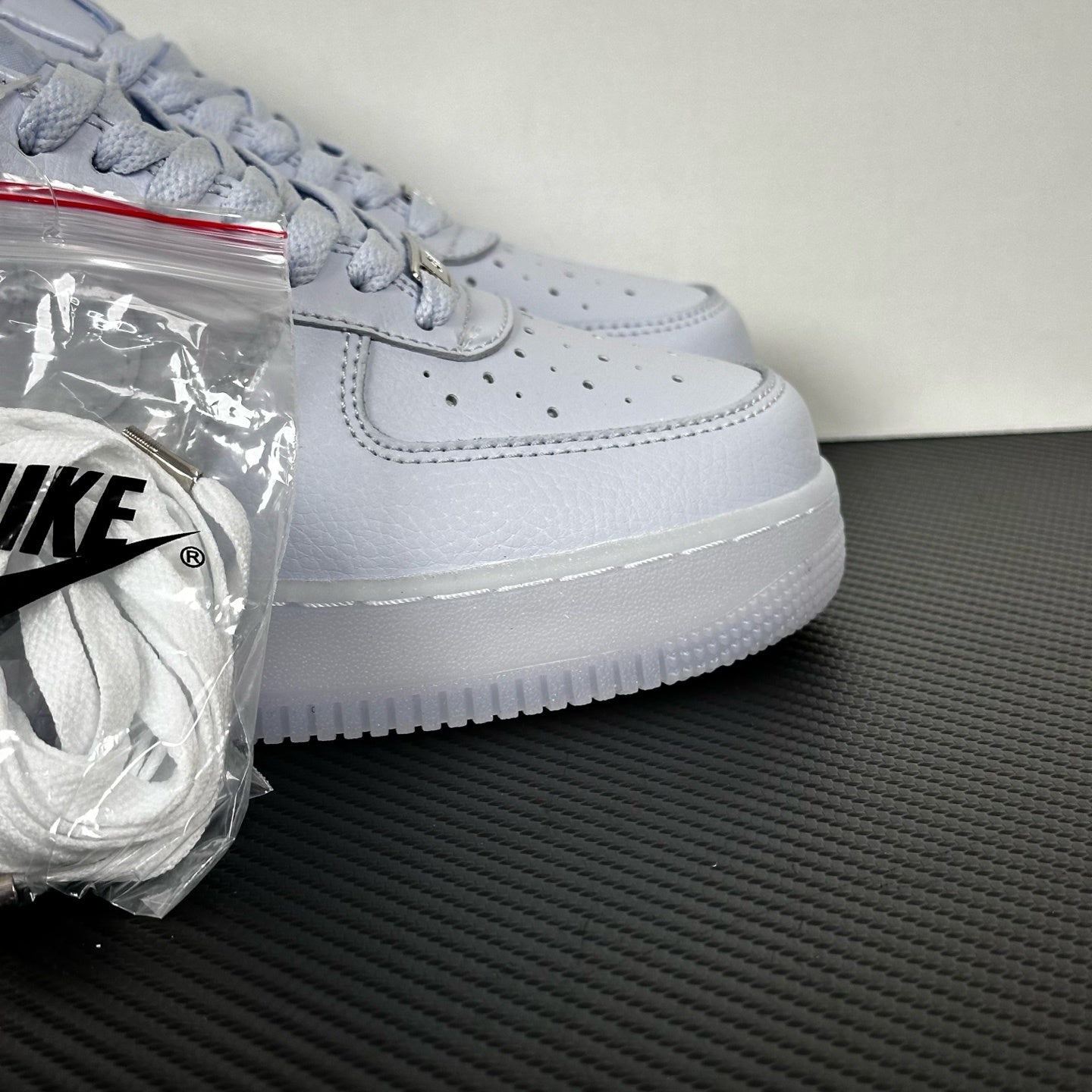 White leather low-top sneaker, Nike swoosh and lace eyelets, side view, bag