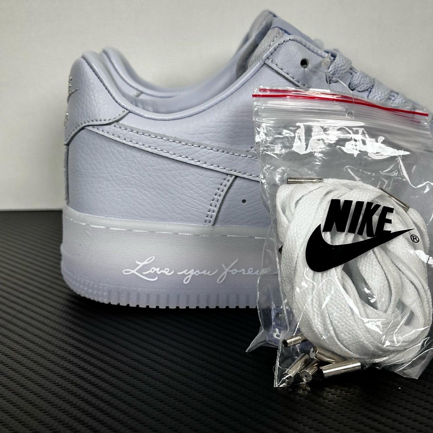 White leather low-top sneaker, Nike swoosh and lace-up front, with accessory bag