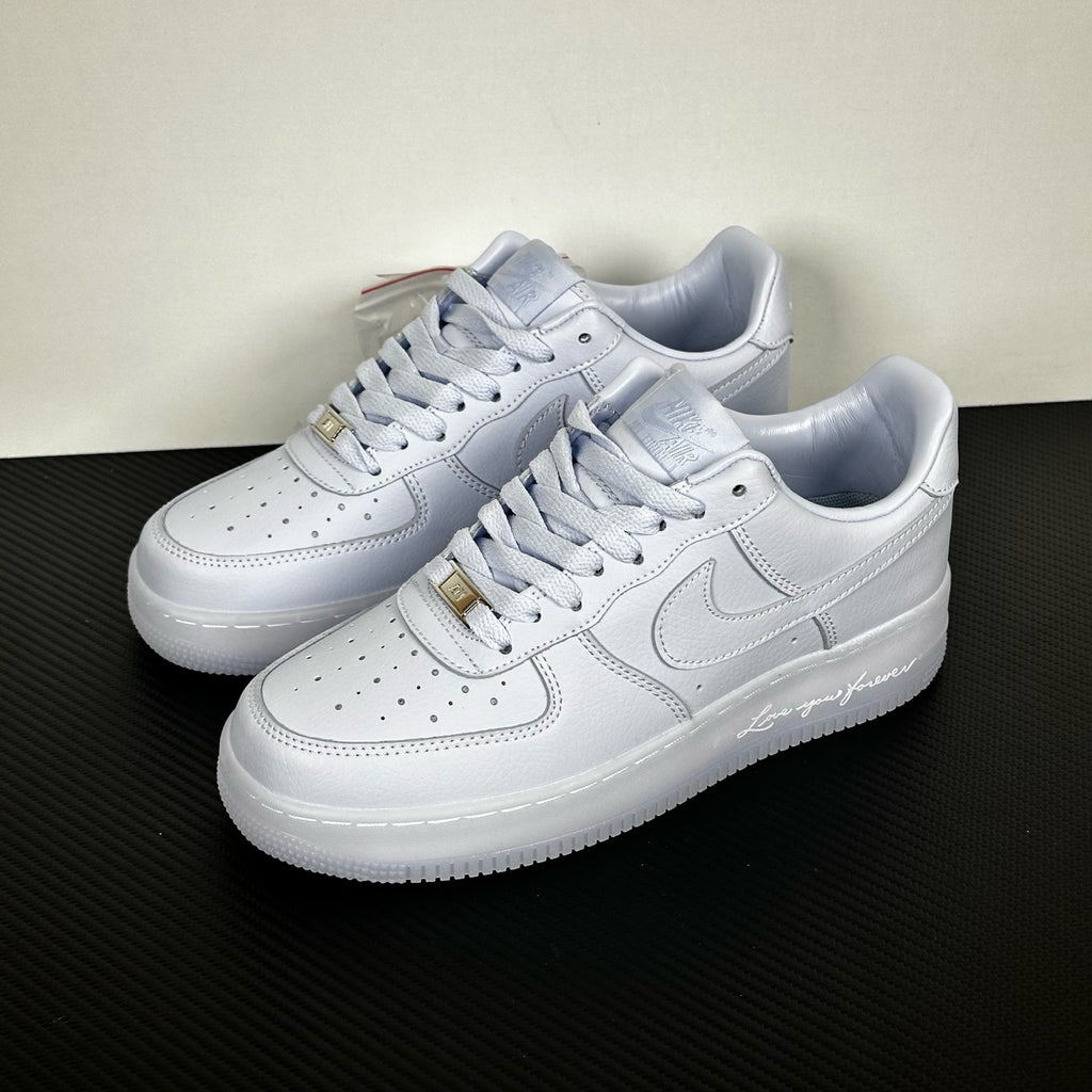 White leather low-top sneakers pair, Nike swoosh and gold lace tips