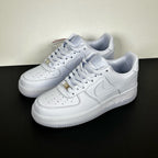 White leather low-top sneakers pair, Nike swoosh and gold lace tips