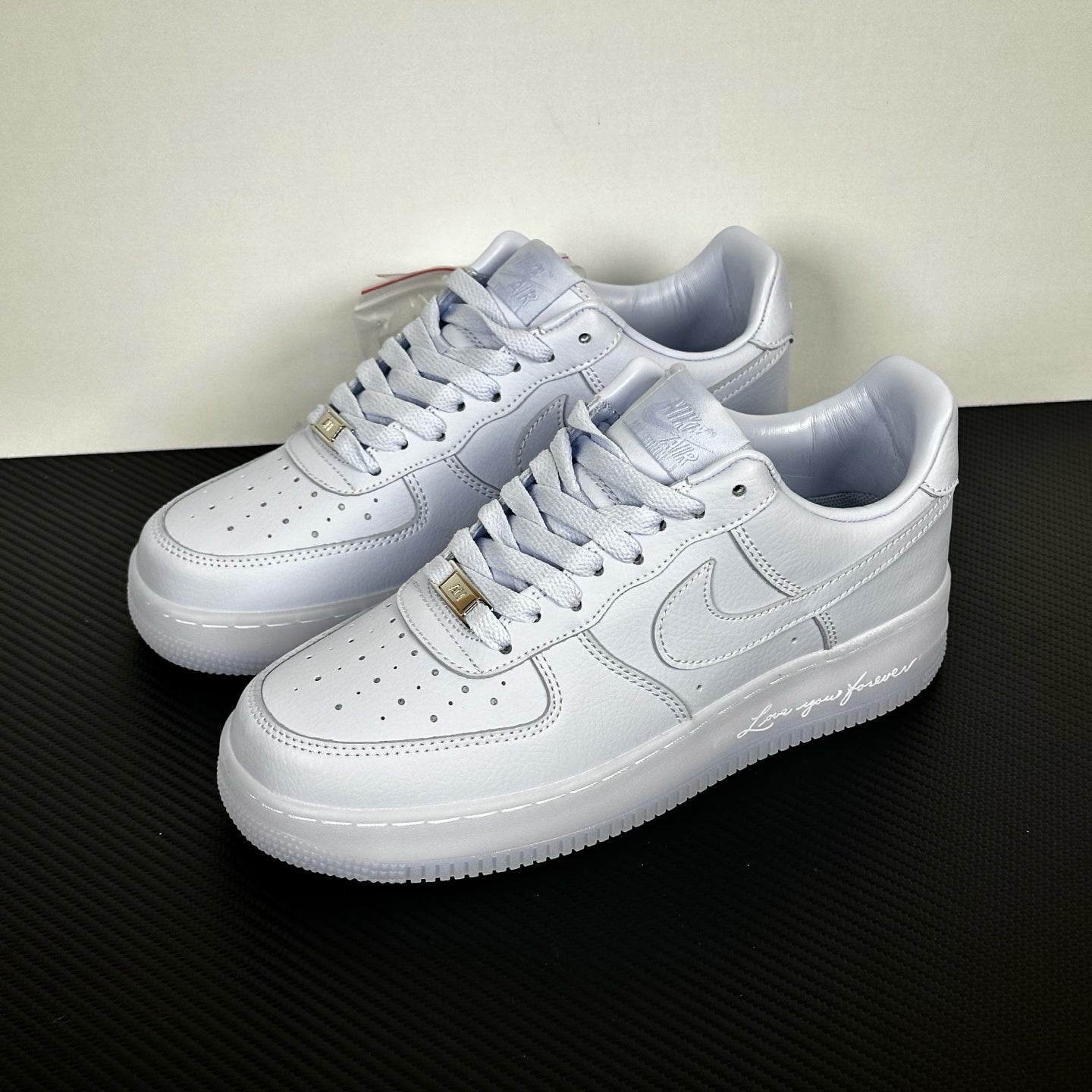 White leather low-top sneakers pair, Nike swoosh and gold lace tips