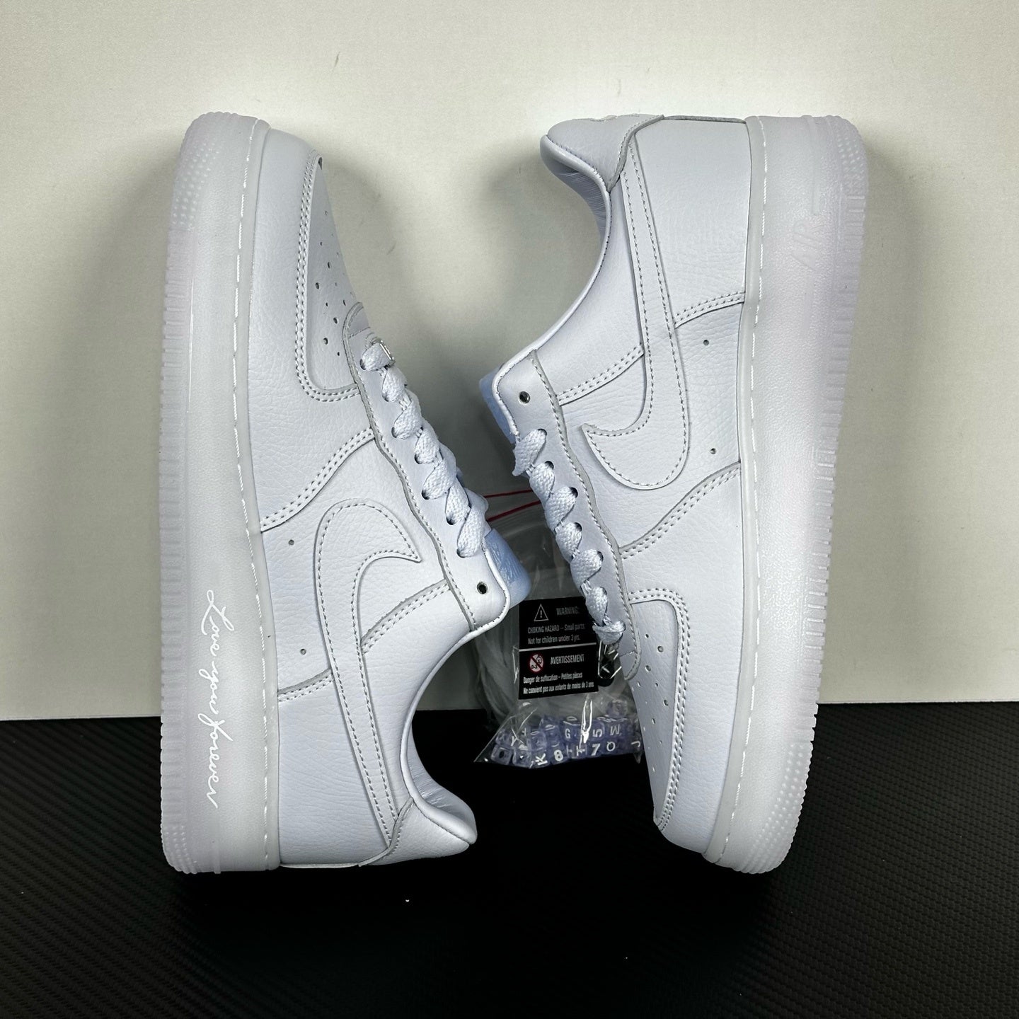 White leather low-top sneakers pair, angled side view, lace-up and swoosh