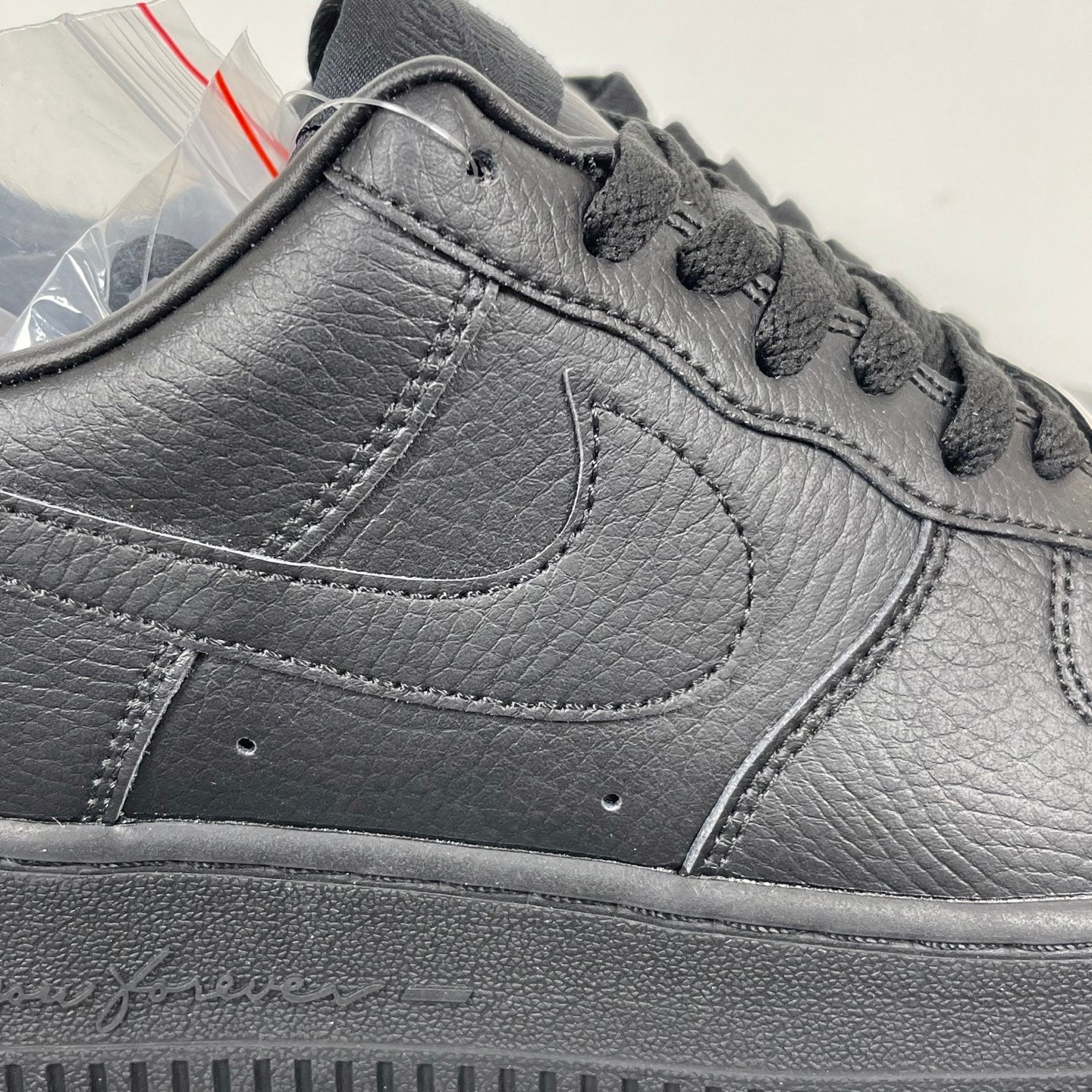 Air Force 1 sneaker upper close-up in dark gray leather, swoosh and lace area stitching