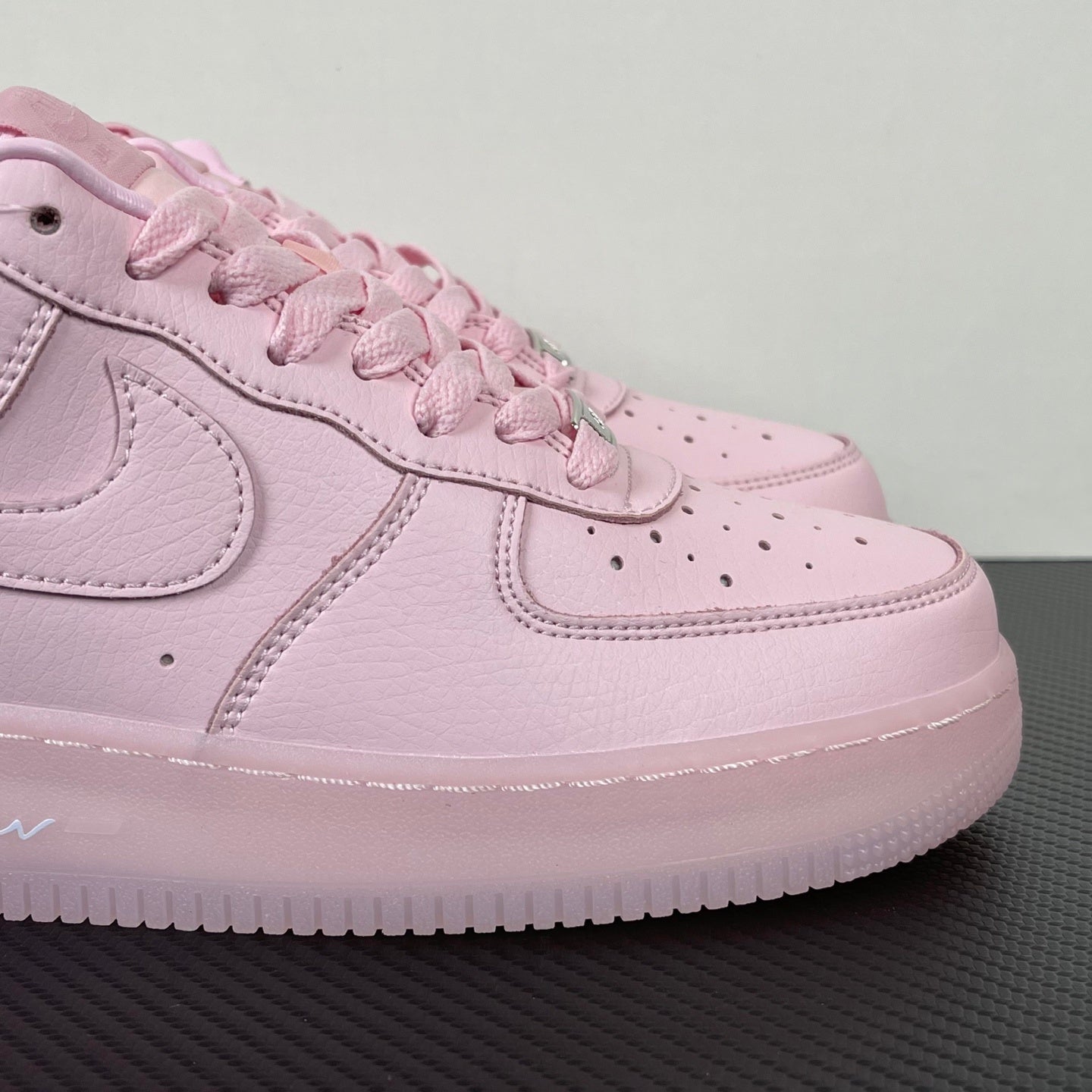 Pink low-top sneaker close-up with textured leather, swoosh and stitched panels