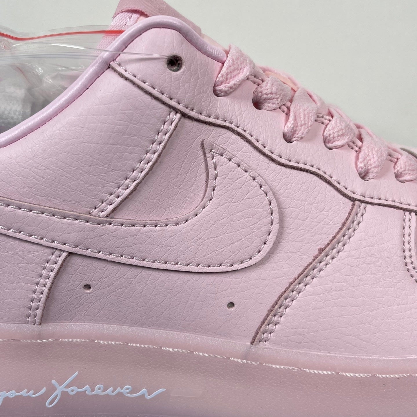 Pink low-top sneaker close-up of swoosh and lace eyelets