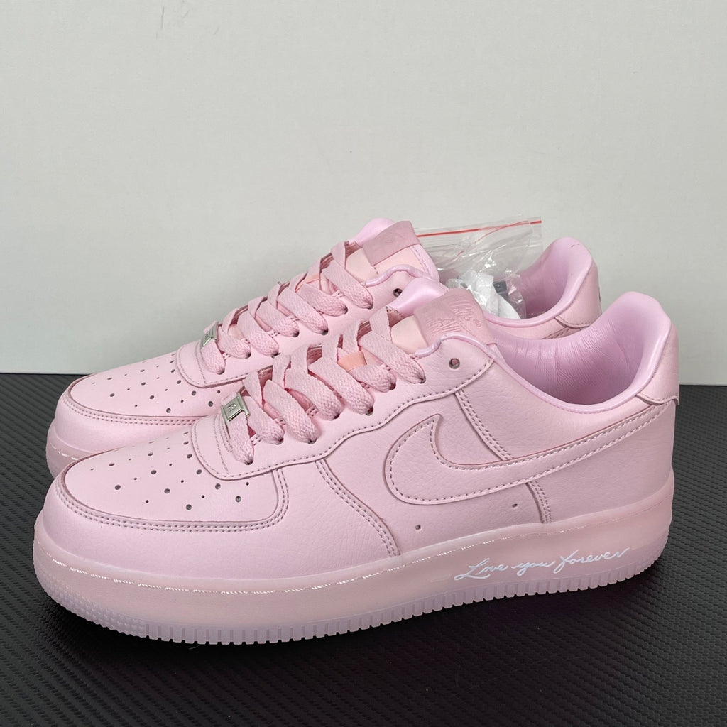 Pink low-top sneakers with lace-up front, swoosh, and perforated toe