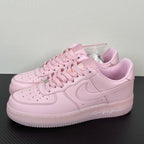Pink low-top sneakers with lace-up front, swoosh, and perforated toe