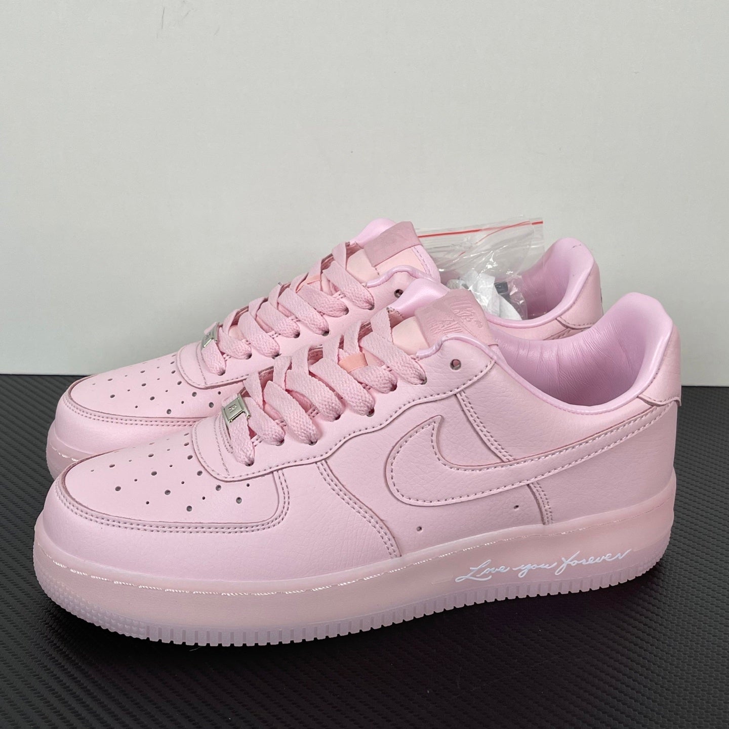Pink low-top sneakers with lace-up front, swoosh, and perforated toe