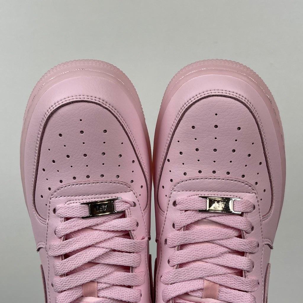 Pink low-top sneakers with perforated toe and two metallic lace eyelets