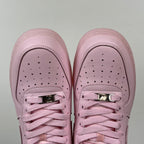 Pink low-top sneakers with perforated toe and two metallic lace eyelets