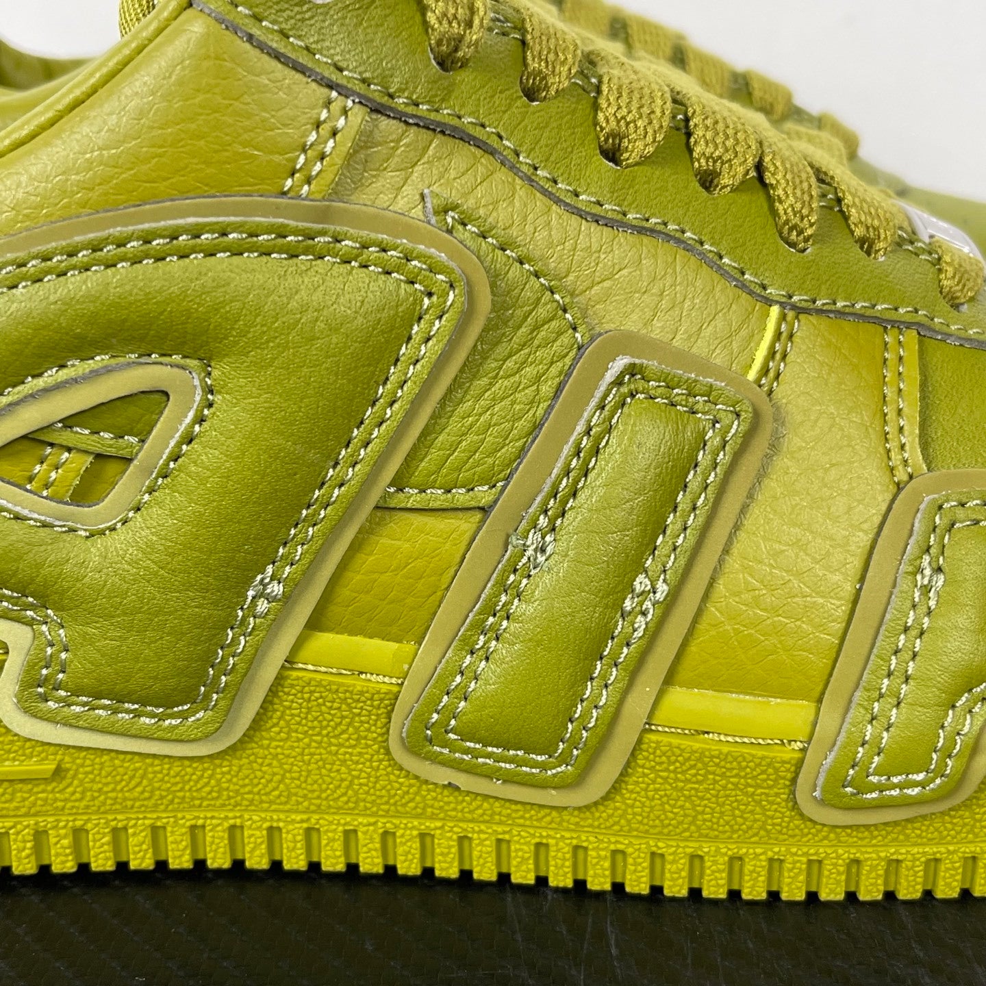 Lime green Air Force 1 sneaker close-up of side panel stitching and lace area