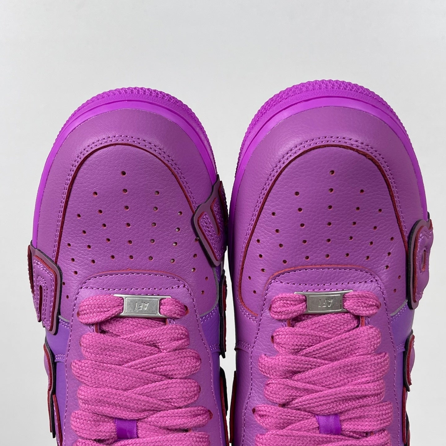 Purple Nike Air Force 1 sneakers, front view with pink lace-up closure and perforations